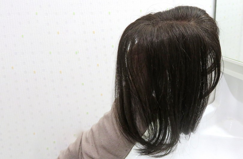 ダークブラウンのショートウィッグを着用した女性の後ろ姿