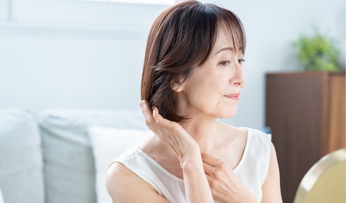 毛先に手を添えて鏡を見る女性